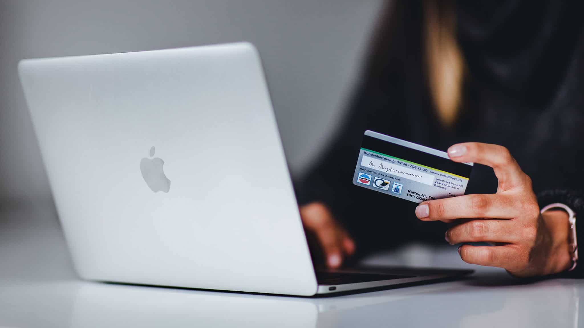 Close up of woman with payment card using a macbook