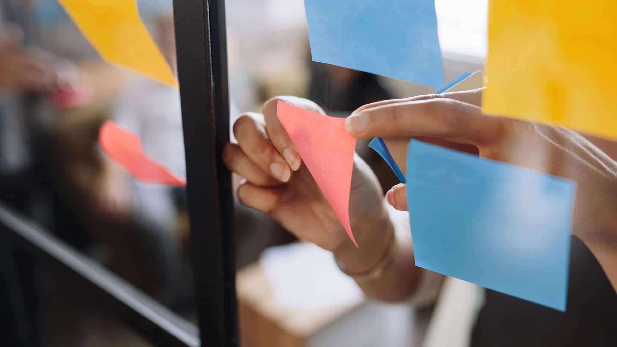 Close up of women's hands placing post-it notes on glass