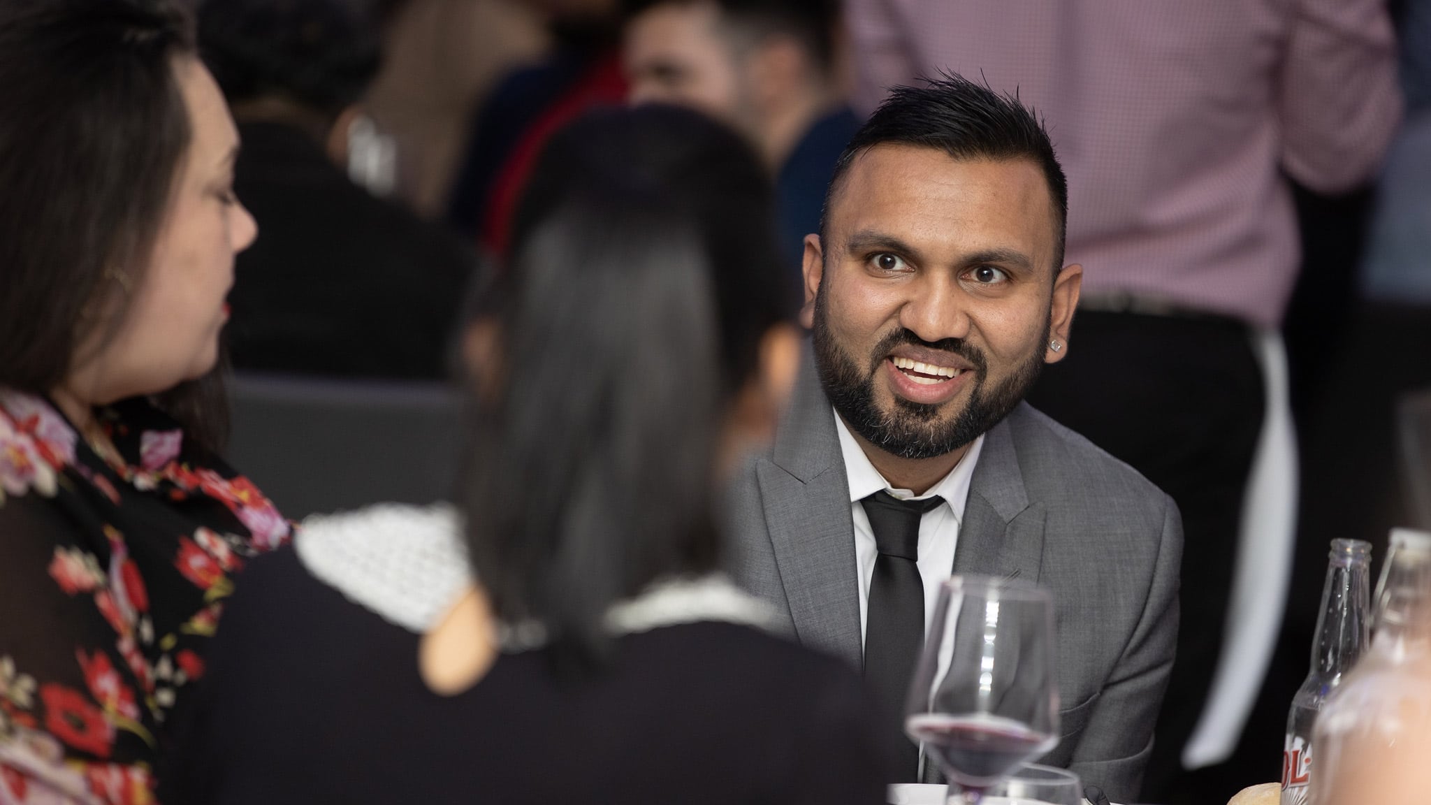Over the shoulder shot of man with beard in grey suit smiling